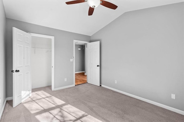 unfurnished bedroom featuring carpet floors, a closet, a ceiling fan, vaulted ceiling, and baseboards