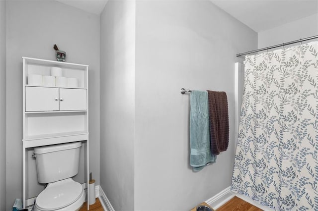 bathroom featuring toilet, baseboards, wood finished floors, and a shower with shower curtain