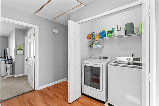 clothes washing area with laundry area, baseboards, light wood-style floors, washer and clothes dryer, and attic access