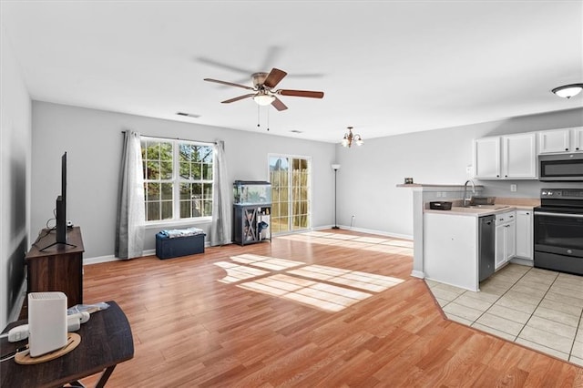 kitchen featuring stainless steel appliances, light countertops, visible vents, light wood-style flooring, and open floor plan