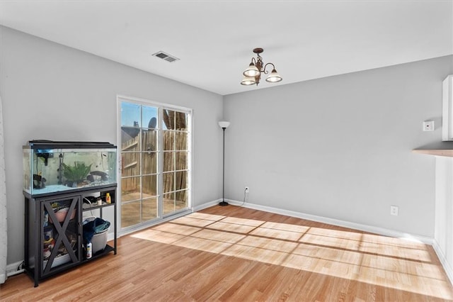 unfurnished dining area with light wood-type flooring, visible vents, a chandelier, and baseboards