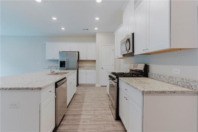 kitchen with appliances with stainless steel finishes, white cabinetry, recessed lighting, light wood-type flooring, and a sink
