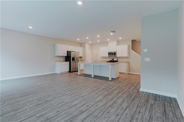 kitchen featuring stainless steel appliances, open floor plan, light countertops, white cabinetry, and light wood finished floors