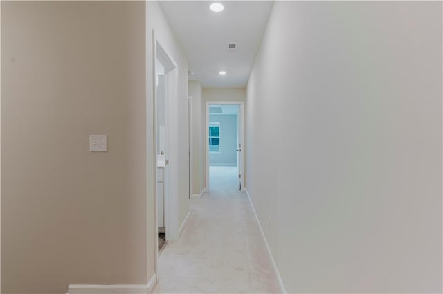 corridor with baseboards, recessed lighting, and light carpet