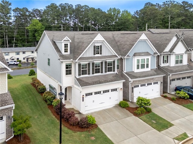 view of front of house featuring an attached garage, concrete driveway, a front lawn, and roof with shingles