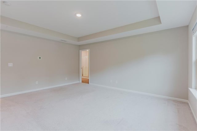 empty room featuring light carpet, baseboards, a tray ceiling, recessed lighting, and a smoke detector