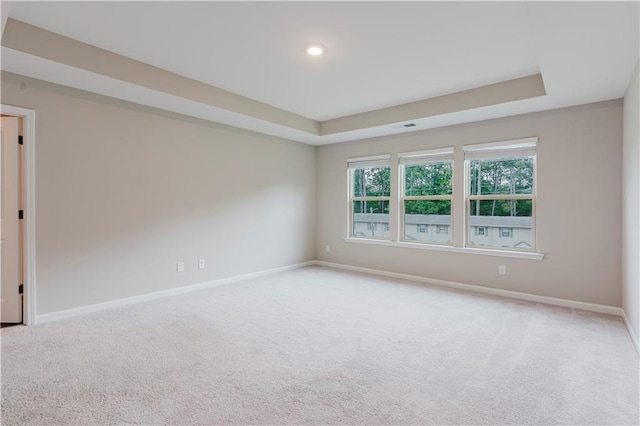 carpeted empty room with baseboards and a tray ceiling