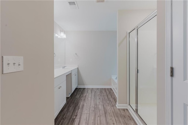 bathroom featuring a shower stall, vanity, wood finished floors, and a garden tub