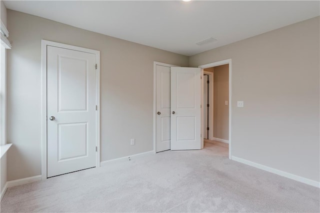 unfurnished bedroom featuring light colored carpet and baseboards