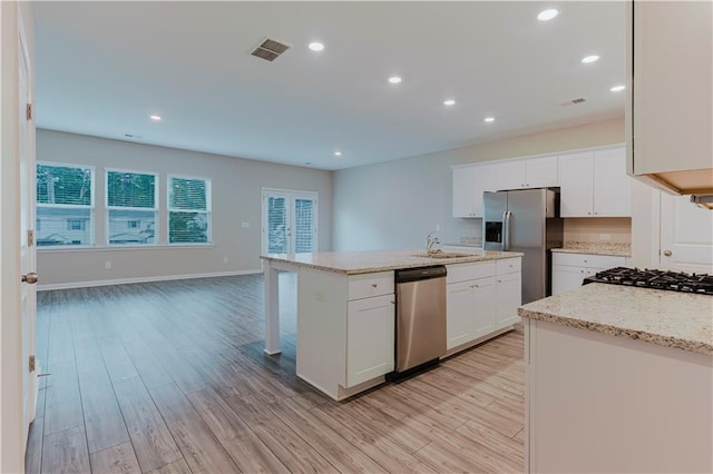 kitchen with stainless steel appliances, light wood-style flooring, a sink, a kitchen island with sink, and white cabinets