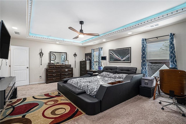 carpeted bedroom featuring a tray ceiling and ceiling fan