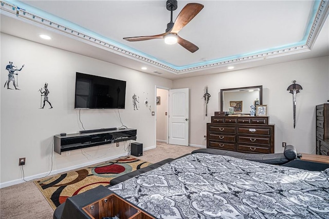 carpeted bedroom with a tray ceiling and ceiling fan