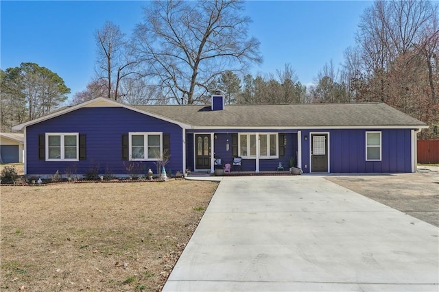 ranch-style house featuring board and batten siding, driveway, a chimney, and a shingled roof