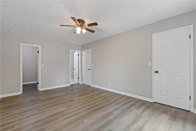 2599 Willow Creek Dr, Duluth, GA 30096 - unfurnished bedroom featuring wood finished floors, baseboards, a ceiling fan, a walk in closet, and a textured ceiling