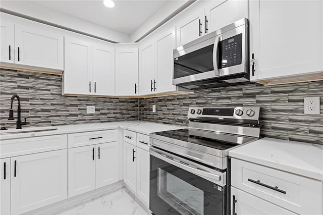 2599 Willow Creek Dr, Duluth, GA 30096 - kitchen featuring stainless steel appliances, a sink, light marble finish flooring, white cabinetry, and backsplash