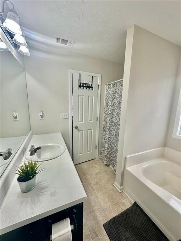 full bath with vanity, a bath, visible vents, a textured ceiling, and tile patterned flooring