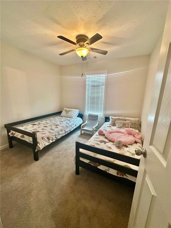 carpeted bedroom with a ceiling fan and a textured ceiling
