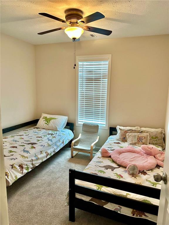 bedroom with a textured ceiling, a ceiling fan, and carpet