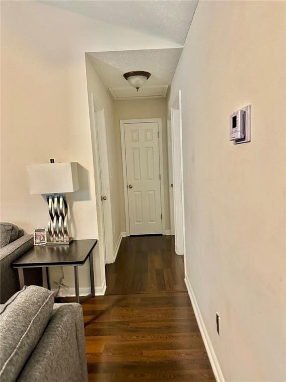 corridor with attic access, dark wood-style floors, and baseboards