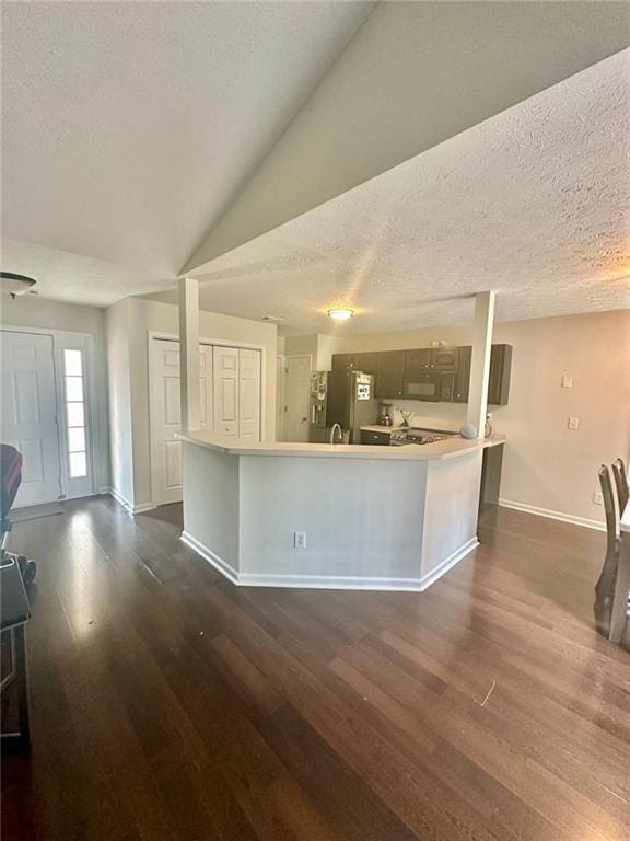 kitchen with a textured ceiling, light countertops, dark wood-style floors, baseboards, and stainless steel refrigerator with ice dispenser