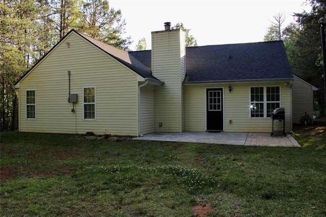 rear view of property with a chimney, a lawn, and a patio area