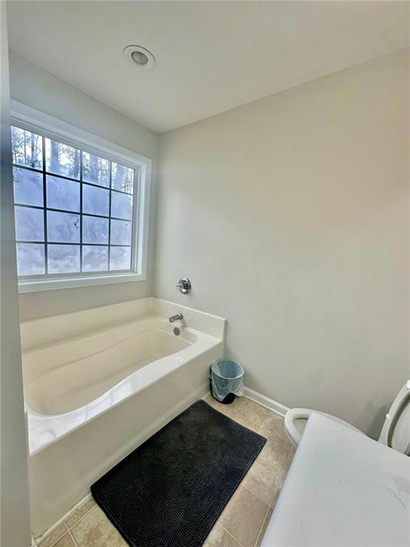 full bathroom with tile patterned floors, a garden tub, and baseboards