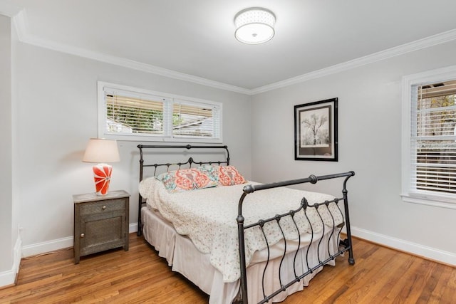 bedroom featuring multiple windows, crown molding, and light wood-type flooring