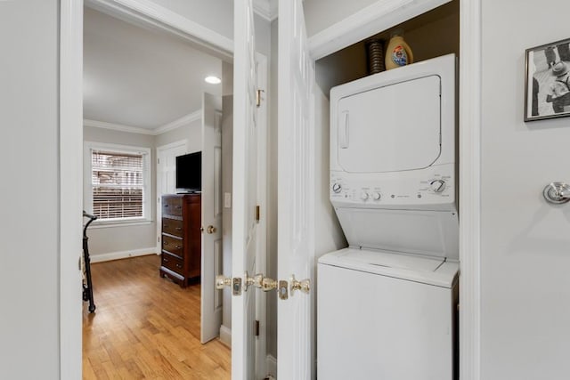 laundry room featuring light hardwood / wood-style floors, stacked washer / drying machine, and ornamental molding