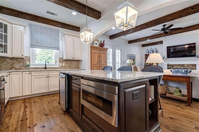 kitchen with a chandelier, light wood-style flooring, tasteful backsplash, plenty of natural light, and beamed ceiling
