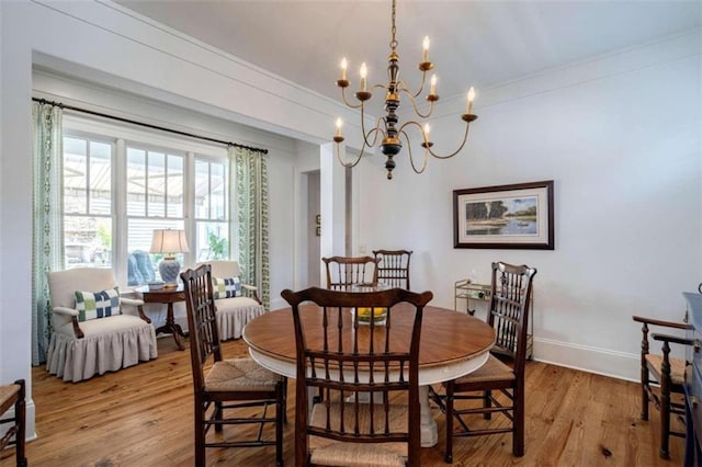 dining area with crown molding, a chandelier, light wood-style floors, and baseboards