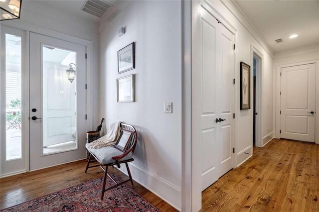 foyer entrance featuring light wood-style flooring, baseboards, and ornamental molding