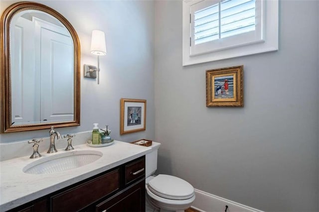 half bath featuring vanity and toilet