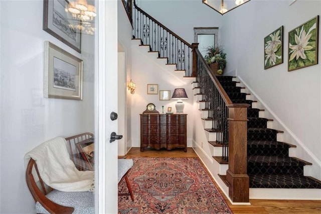 staircase with wood finished floors, a chandelier, and baseboards