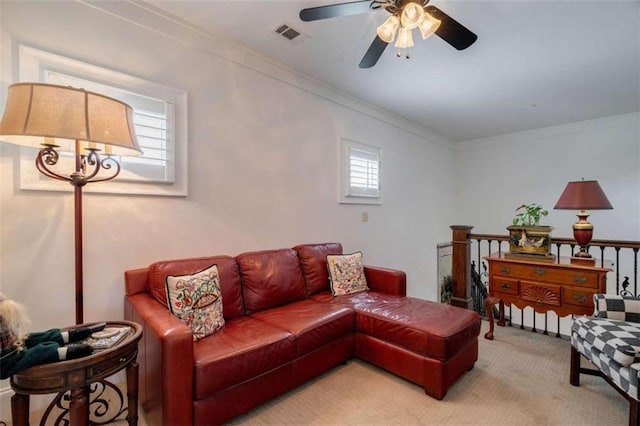 living area featuring ceiling fan, light colored carpet, and crown molding