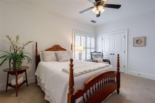 bedroom featuring light carpet, a closet, ceiling fan, baseboards, and crown molding