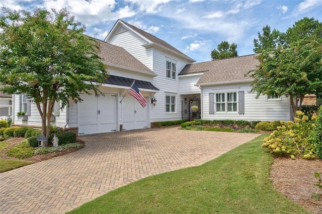 view of front facade featuring decorative driveway, an attached garage, a shingled roof, and a front yard