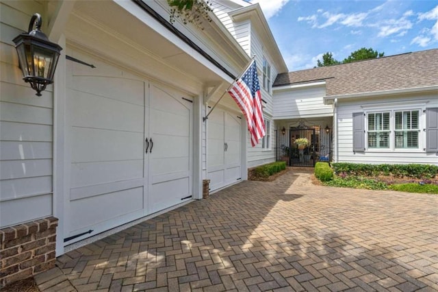 property entrance with decorative driveway and an attached garage