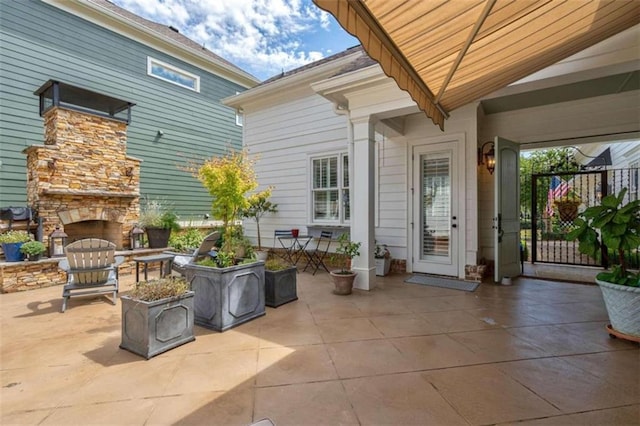 view of patio with an outdoor stone fireplace and a gate