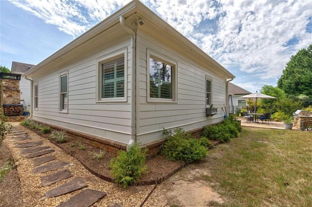 view of side of home featuring a patio and a yard