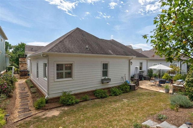 back of property with a patio and roof with shingles