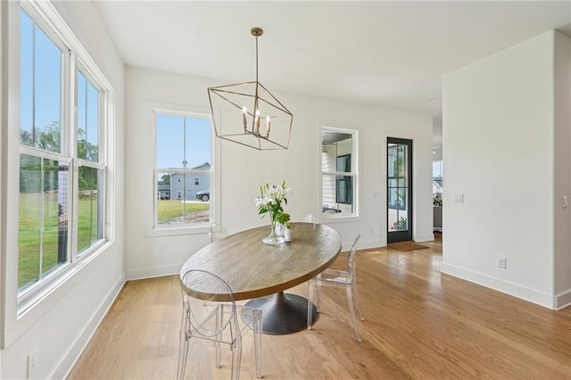 dining area with baseboards, light wood finished floors, and a chandelier