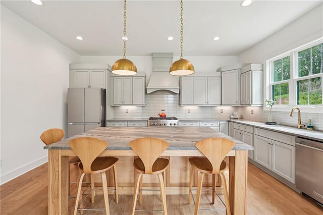 kitchen with freestanding refrigerator, custom exhaust hood, stove, a sink, and dishwasher