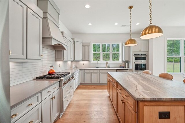 kitchen featuring light stone countertops, light wood-style flooring, stainless steel appliances, recessed lighting, and backsplash