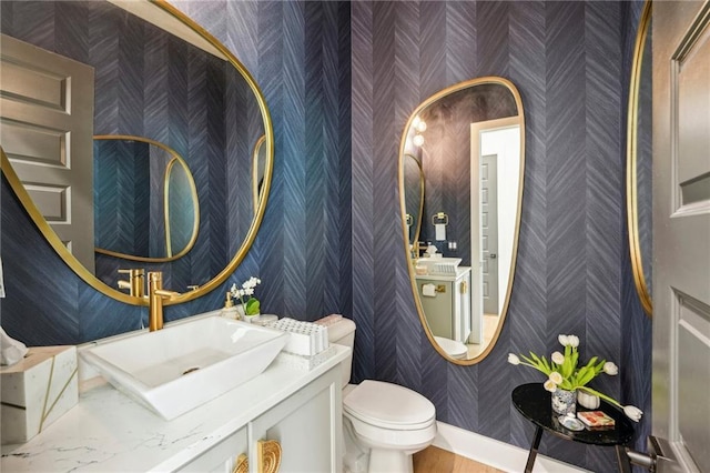bathroom featuring toilet, wallpapered walls, and vanity