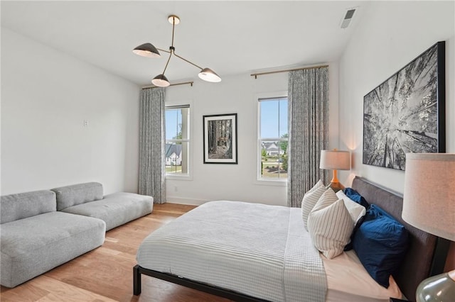 bedroom featuring baseboards, wood finished floors, and visible vents