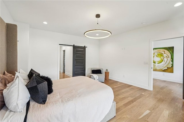 bedroom with recessed lighting, baseboards, light wood finished floors, and a barn door