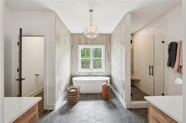 full bathroom featuring a freestanding bath, tile patterned flooring, a stall shower, vanity, and an inviting chandelier