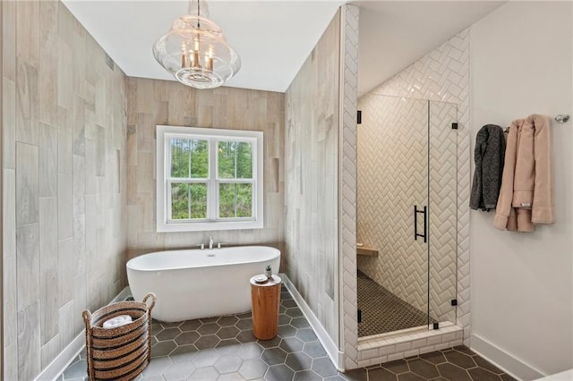 bathroom featuring a freestanding bath, baseboards, tile patterned flooring, and a shower stall
