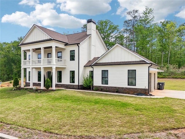neoclassical home with covered porch, board and batten siding, a front yard, and a balcony