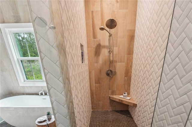 bathroom featuring tile walls, a freestanding bath, a tile shower, and a wealth of natural light